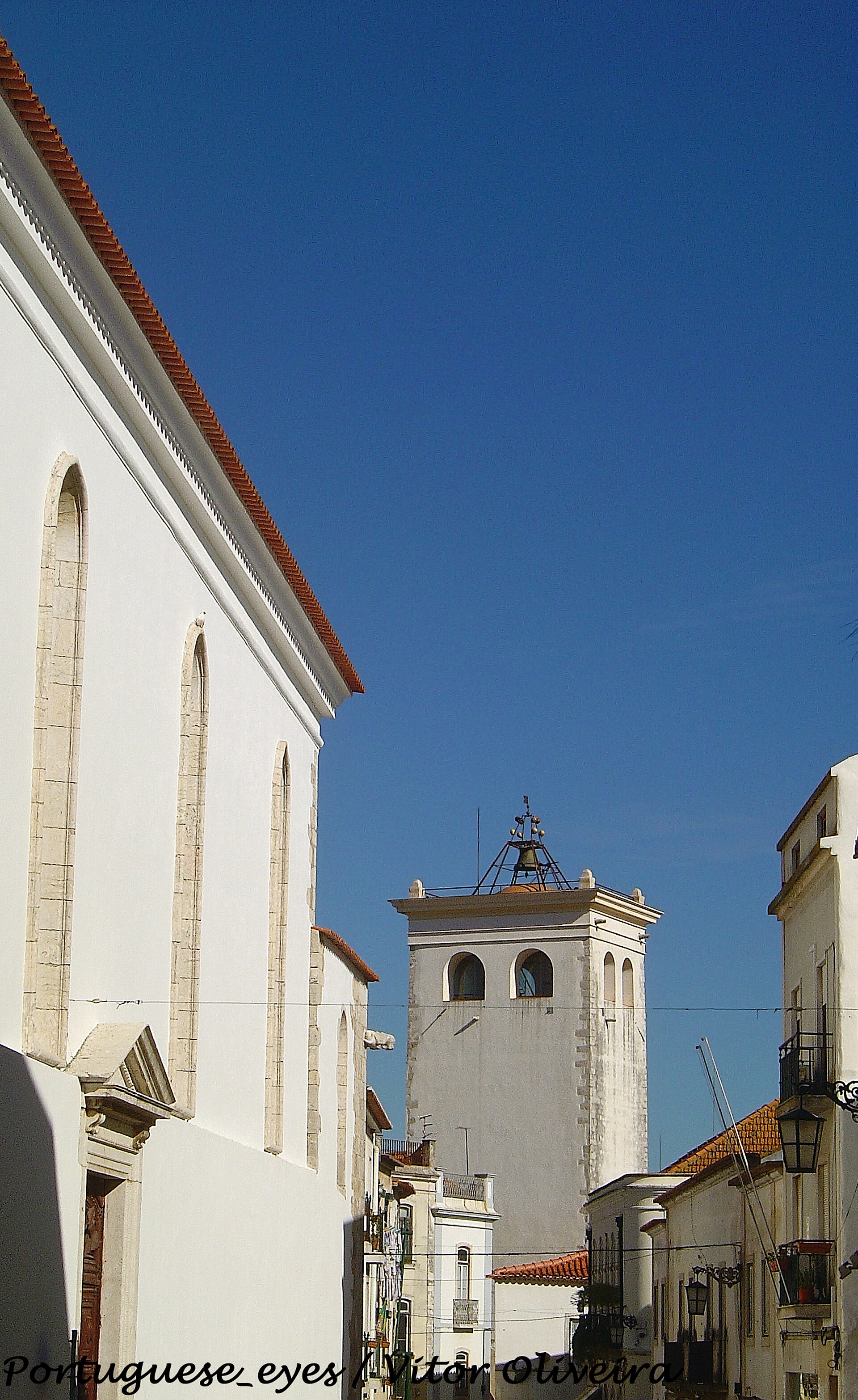 Rua do centro histórico de Santarém com torre sineira