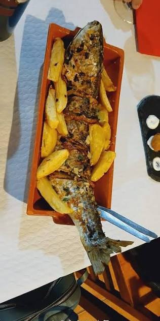 Fataça inteira assada numa telha de barro, rodeada de batata